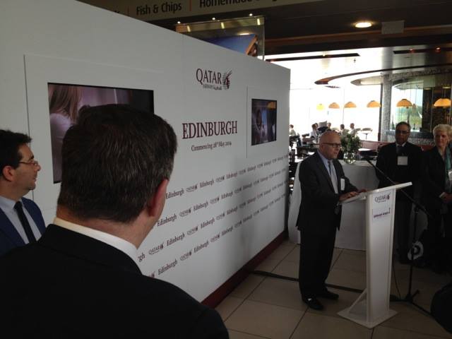 man speaking at a podium about Qatar airlines