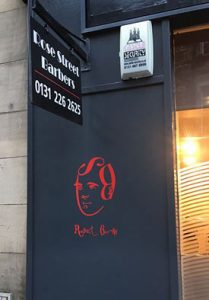 door with face of robbie burns and rose street barbers on it