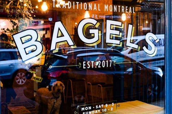 shop window with bagels and traditional montreal written on it. With a dog looking out from inside