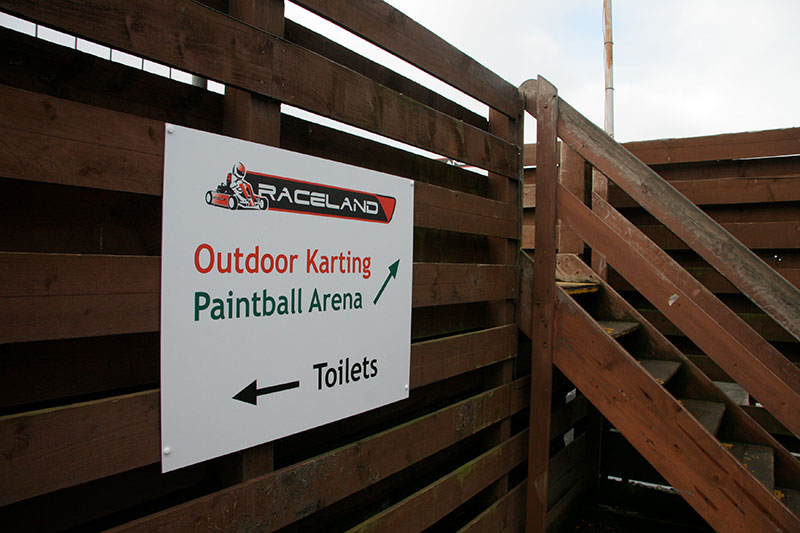 outdoor carting and paintball sign next to wooden stairs