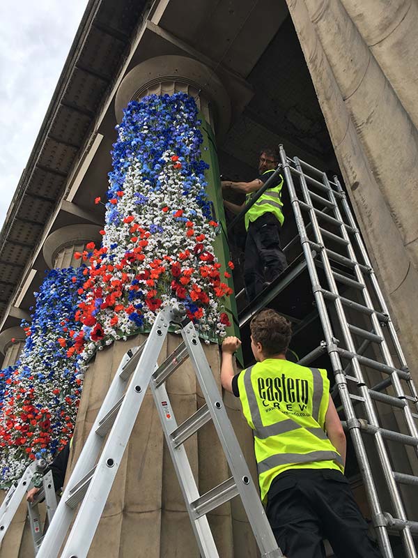 eastern workers up scaffolding fixing signs to pillars