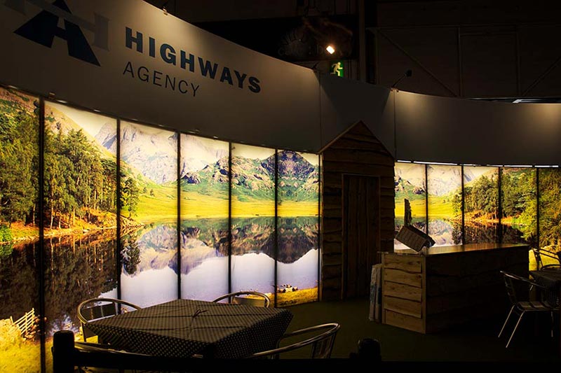 highways agency exhibition stand with seating and chairs and a lake side country scene