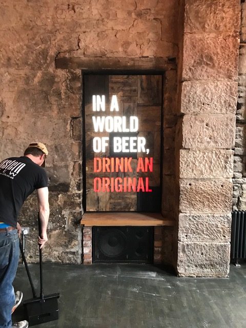 innis & gunn beer message attached to the wall with a man sweeping up in the foreground