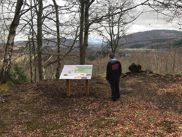 information sign and a member of staff outside in the woods